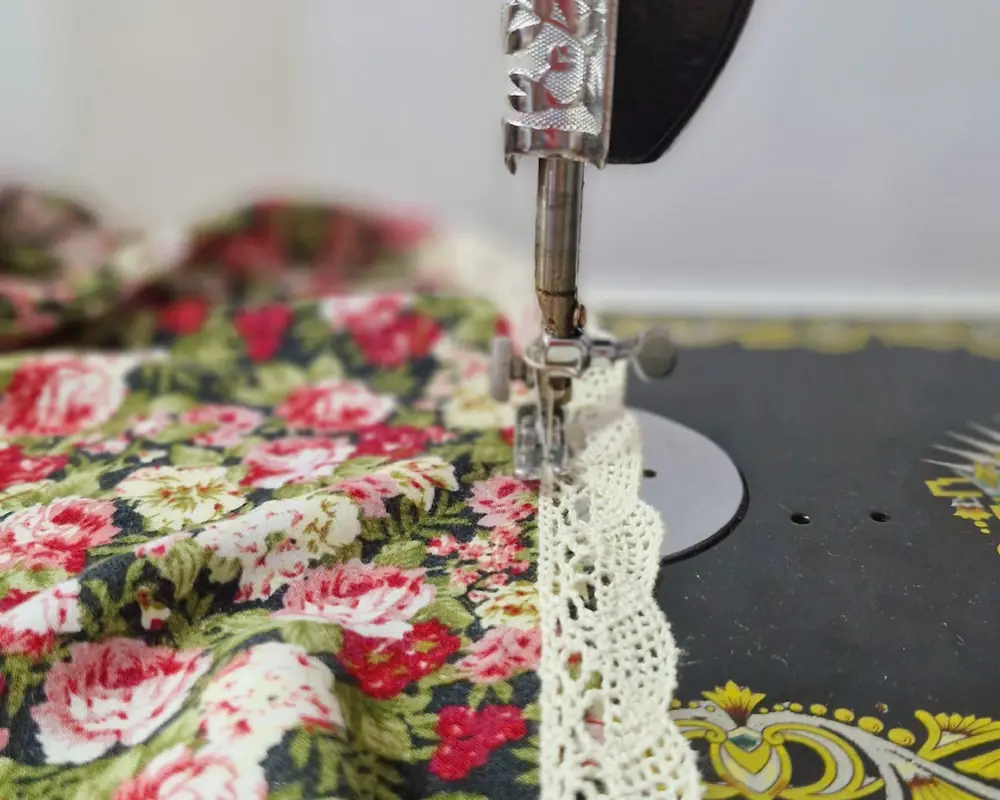 Tela floreada con puntilla pasando por una máquina antigua